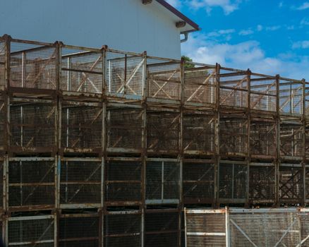 Old rusted transport boxes of metal grid stacked on a house wall