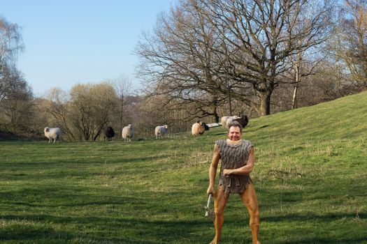 Cartoon illustration of a Neanderthal figure made of plastic with hatchet on a meadow while hunting for sheep