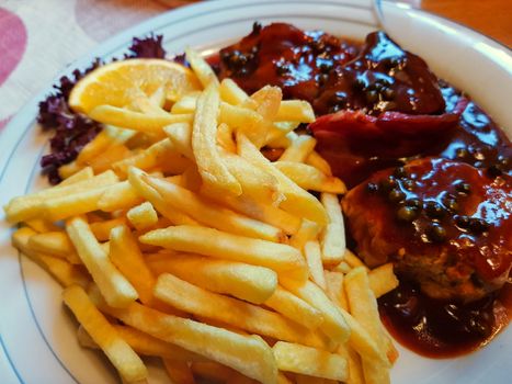 Various grilled meats with french fries on white dish