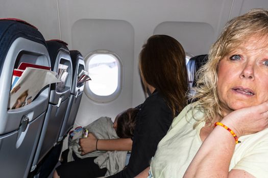 Interior with screens of a modern airplane and passengers waiting for takeoff.