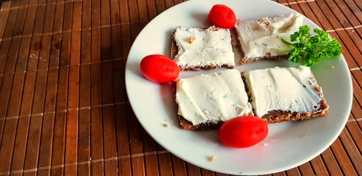 Homemade wholemeal brown bread with cottage cheese and parsley on brown bamboo base.