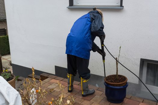 Woman cleans stone slabs with a pressure washer