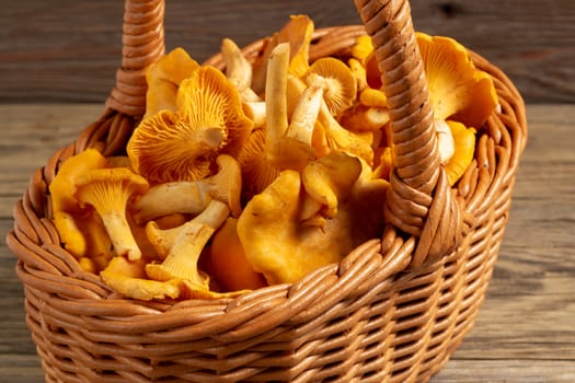 Wicker basket with chanterelles over an old wooden table.