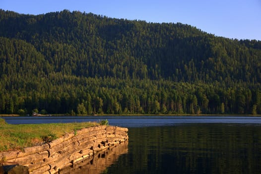 A fragment of a pier overlooking a mountain lake at sunset. Teletskoye Lake, Altai, Siberia, Russia.