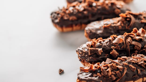 Set of homemade eclairs with chocolate on marble background. Close up view of delicious healthy profitroles with chocolate glaze. Copy space for text or design. Banner