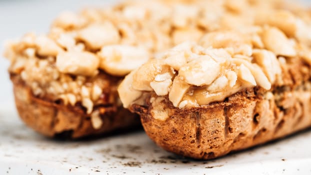 Homemade eclairs with peanut on marble background. Close up view of delicious healthy profitroles with nuts. Copy space for text or design.