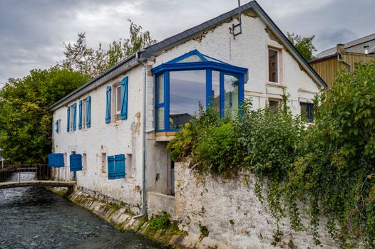 Old house along the river of tone with blue shutters in the city of Virton in the province of Luxembourg in Belgium