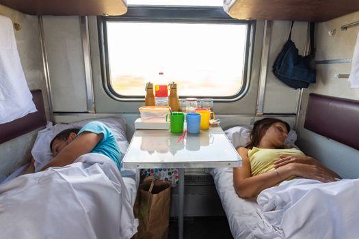 Man and woman sleep on lower shelves in a train car