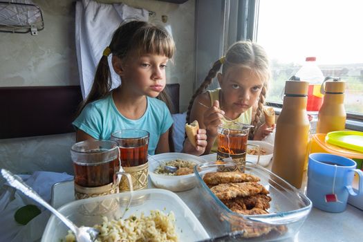 Two girls have lunch in the reserved seat of the train
