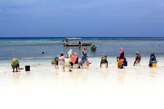 Nungwi, Zanzibar, Tanzania - January 11, 2016:  African women in traditional dress on the beach of village Nungwi. Zanzibar, Tanzania