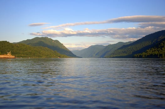 Scenic view of the evening mountain lake surrounded by mountains covered with coniferous forest. Altai, Siberia, Russia.