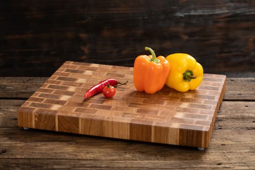 Ripe, bright peppers lie on a wooden cutting board. Cutting vegetables for cooking. Fresh, ripe, tasty, natural vegetable.