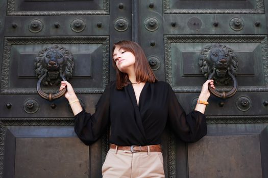 Beautiful young woman near old iron building door