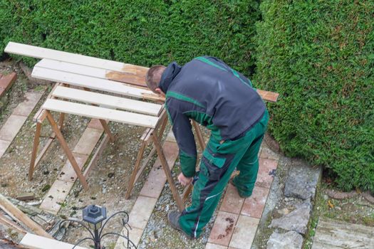 Man with a paintbrush stroking wooden beams.