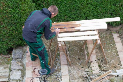 Man with a paintbrush stroking wooden beams.