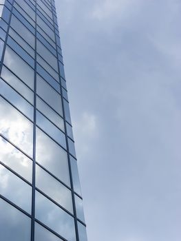 Cloudy sky reflected in the glass wall of a high building.
