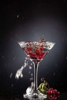 Bunch of red currant falling into the glass of water