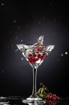 Bunch of red currant falling into the glass of water