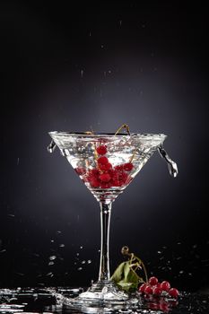 Bunch of red currant falling into the glass of water