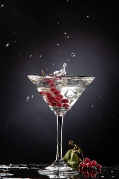 Bunch of red currant falling into the glass of water