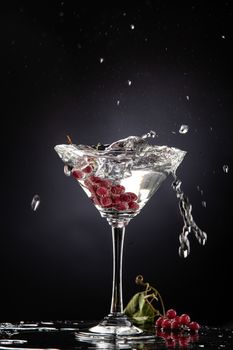 Bunch of red currant falling into the glass of water
