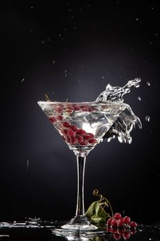Bunch of red currant falling into the glass of water