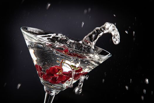 Bunch of red currant falling into the glass of water