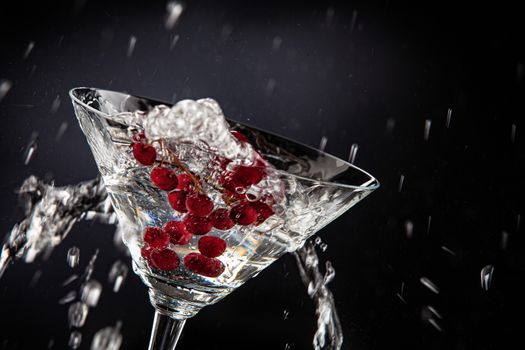 Bunch of red currant falling into the glass of water