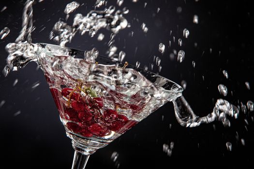 Bunch of red currant falling into the glass of water