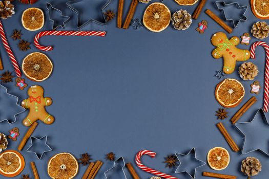 Christmas food frame. Gingerbread cookies, spices and decorations on blue background with copy space