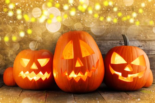 Three halloween pumpkins in magic golden bokeh lights around