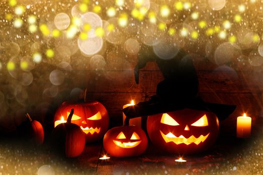 Halloween jack o lantern carved pumpkin wearing witches hat in magic golden bokeh lights around