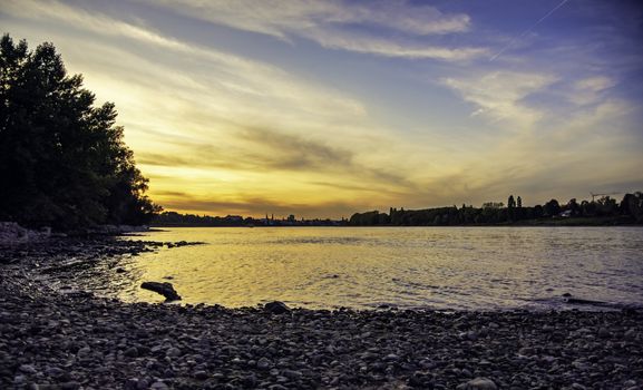 Beautiful orange sunset seen from a tiny pebbled beach by the Rheine river in Bonn.