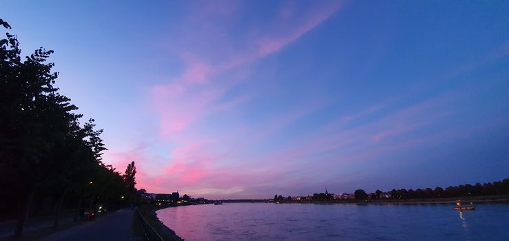 Promenade by the river Rheine in Bonn with a beautiful pink sunset sky.