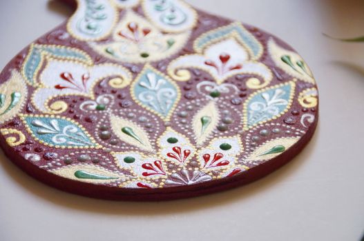 Handpainted pomegranate with intricate ornate pattern, made from wood, painted with acrylic colors. Ornamental design on a red bakground.