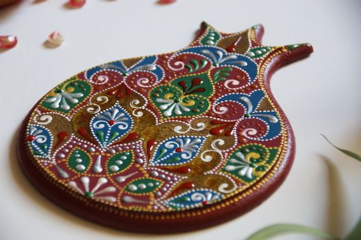 Handpainted pomegranate with intricate ornate pattern, made from wood, painted with acrylic colors. Ornamental design on a red bakground.