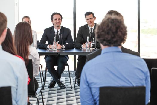 Group of speakers at business meeting at the table with microphones