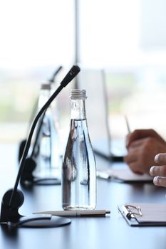 Microphones and water at conference table, business meeting concept