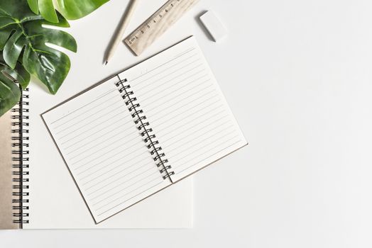 Flat lay of white office desk table with blank notebook, supplies and coffee cup. Top view with copy space.