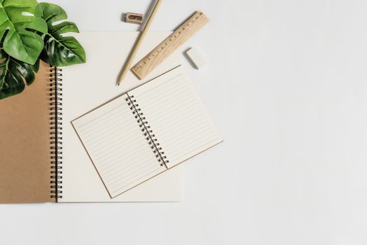 Flat lay of white office desk table with blank notebook, supplies and coffee cup. Top view with copy space.