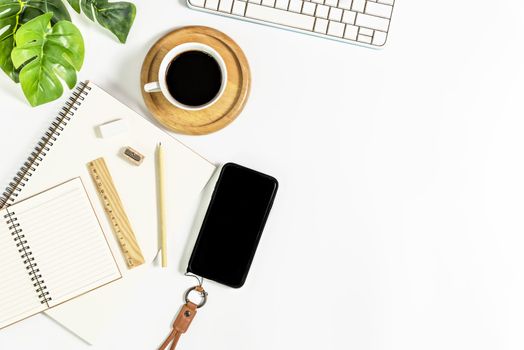 Flat lay of white office desk table with blank notebook, supplies and coffee cup. Top view with copy space.