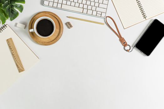 Flat lay of white office desk table with blank notebook, supplies and coffee cup. Top view with copy space.