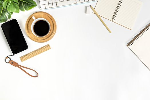 Flat lay of white office desk table with blank notebook, supplies and coffee cup. Top view with copy space.