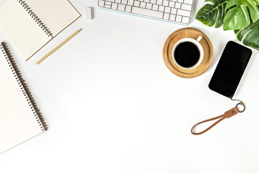 Flat lay of white office desk table with blank notebook, supplies and coffee cup. Top view with copy space.