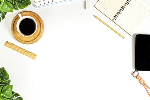 Flat lay of white office desk table with blank notebook, supplies and coffee cup. Top view with copy space.