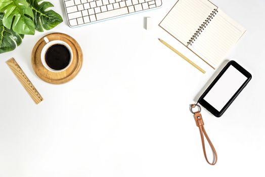 Flat lay of white office desk table with blank notebook, supplies and coffee cup. Top view with copy space.