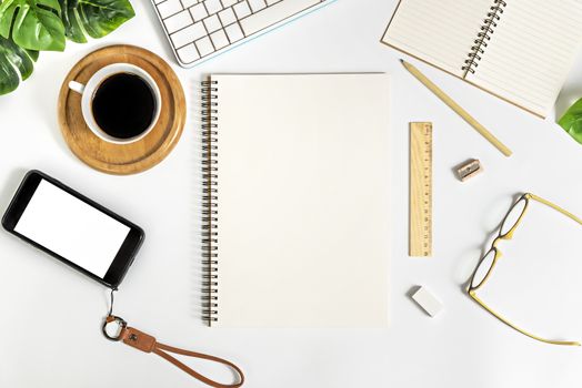 Flat lay of white office desk table with blank notebook, supplies and coffee cup. Top view with copy space.