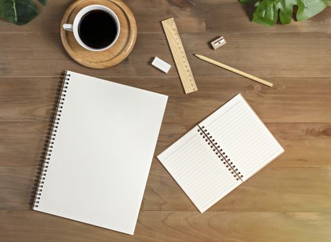 Flat lay of wooden office desk table with blank notebook, supplies and coffee cup. Top view with copy space.