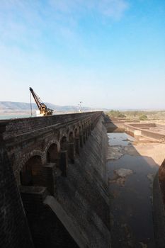 A long stretch of a strong but old dam wall made of black stones .