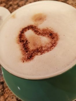 Green cup of coffee with foam and heart